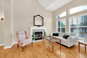 Living room featuring vaulted ceiling, bight window, hardwood floors and a wood-burning fireplace