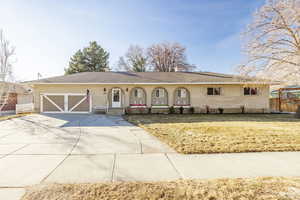 Ranch-style home with a porch, a garage, and a front yard