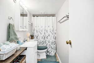 Bathroom featuring a shower with curtain, vanity, a textured ceiling, and toilet