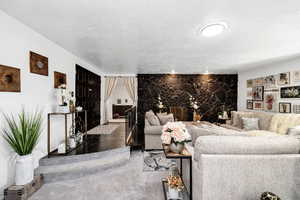 Living room with dark colored carpet, a textured ceiling, and a fireplace