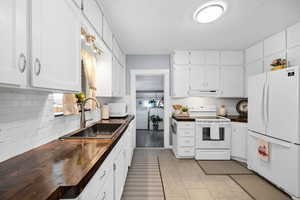 Kitchen with white cabinetry, sink, white appliances, and decorative backsplash