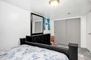 Carpeted bedroom with a closet and a textured ceiling