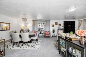 Carpeted dining room with a chandelier and a textured ceiling