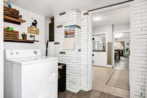 Clothes washing area with light tile patterned flooring, brick wall, and washer / dryer