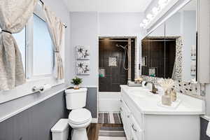 Full bathroom featuring tiled shower / bath combo, vanity, hardwood / wood-style floors, and toilet