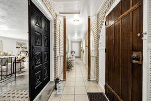 Hall featuring light tile patterned floors and a textured ceiling