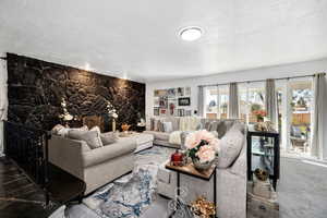 Carpeted living room featuring a fireplace and a textured ceiling