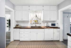 Kitchen featuring sink, white appliances, butcher block counters, backsplash, and white cabinets