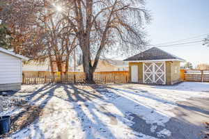 Snowy yard featuring a shed