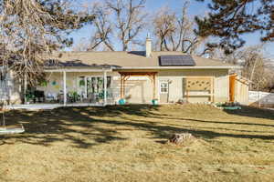 Back of property featuring a yard, a patio, and solar panels