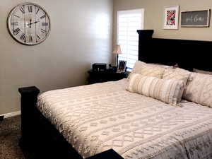 Bedroom with vaulted ceiling, dark carpet, and ceiling fan