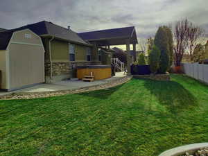 View of yard featuring a storage shed, a hot tub, and a patio area