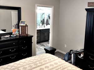 Carpeted bedroom featuring ceiling fan, connected bathroom, and vaulted ceiling