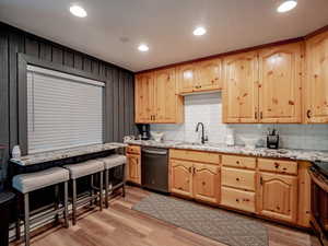 Breakfast bar, kitchen with sink, granite counter tops with custom cabinets, lvp flooring, appliances with stainless steel finishes, and decorative backsplash