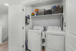 Laundry area with washing machine and dryer and light colored carpet