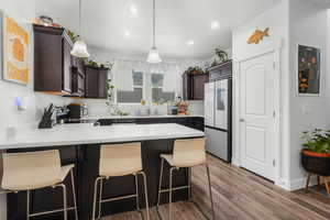 Kitchen featuring pendant lighting, a breakfast bar, appliances with stainless steel finishes, dark brown cabinetry, and kitchen peninsula