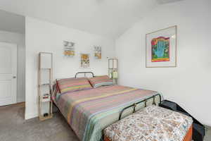 Carpeted bedroom with lofted ceiling