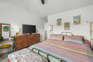 Carpeted bedroom featuring ceiling fan and vaulted ceiling