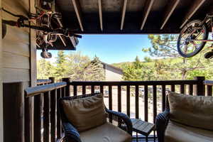 Comfortable balcony with cozy chairs and two mountain bikes hung from rafters.