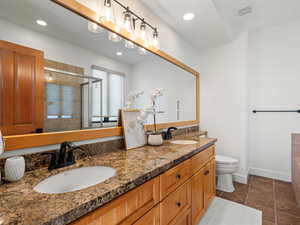 Bathroom featuring vanity, a shower with shower door, and toilet