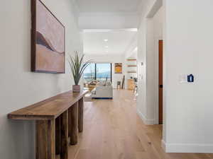 Hall with light hardwood / wood-style flooring and ornamental molding