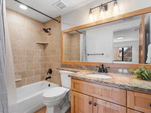 Full bathroom with vanity, shower / bath combination with curtain, and toilet