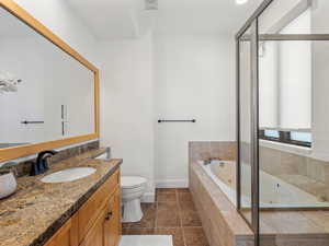 Bathroom with toilet, vanity, and tiled bath