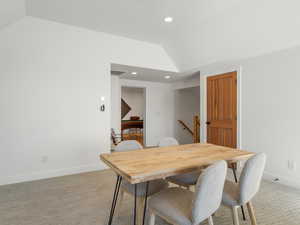 Dining room featuring vaulted ceiling and light carpet