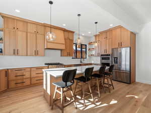 Kitchen with pendant lighting, a breakfast bar, stainless steel appliances, a center island, and light hardwood / wood-style floors