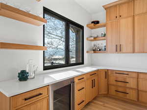 Kitchen with light brown cabinets, beverage cooler, and light wood-type flooring