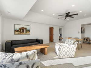 Carpeted living room with vaulted ceiling and ceiling fan