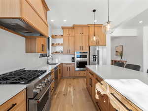 Kitchen featuring premium range hood, appliances with stainless steel finishes, pendant lighting, sink, and light brown cabinets