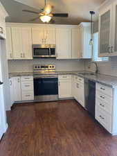 Kitchen featuring pendant lighting, appliances with stainless steel finishes, sink, and white cabinets