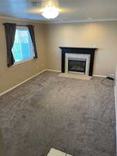 Unfurnished living room featuring ornamental molding, carpet floors, and a textured ceiling