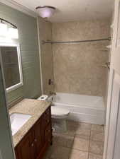 Full bathroom with vanity, toilet, a textured ceiling, and tiled shower / bath