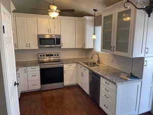 Kitchen featuring sink, stainless steel appliances, hanging light fixtures, and white cabinets