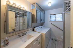 Washroom with cabinets, washing machine and dryer, sink, and light tile flooring