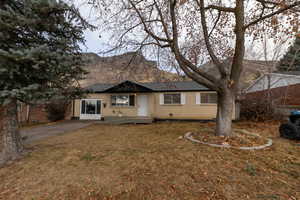 Front view of property with a mountain view and a yard