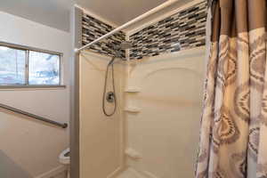 Bathroom featuring toilet and a shower with curtain