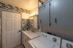 Laundry area with cabinets located in bathroom, sink, and washer and clothes dryer