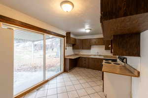 Kitchen with electric stove, light tile patterned flooring, and sink