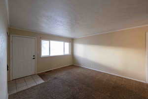 Entryway featuring crown molding, light carpet, and a textured ceiling