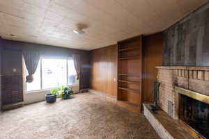 Carpeted family room featuring a fireplace and paneled walls