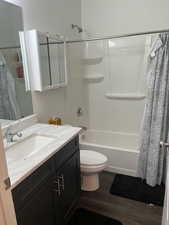 Full bathroom featuring vanity, toilet, hardwood / wood-style floors, and shower / bath combo with shower curtain