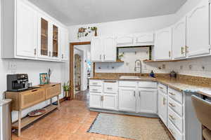 Kitchen with white cabinetry, sink, and stone countertops