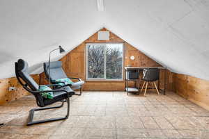 Interior space with lofted ceiling, a textured ceiling, and wood walls