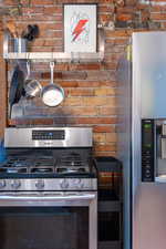 Kitchen featuring brick wall and stainless steel appliances