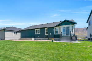 Back of property with a mountain view and a lawn