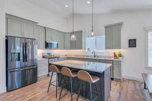 Kitchen featuring sink, a breakfast bar area, a center island, hanging light fixtures, and stainless steel appliances