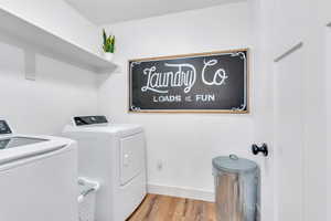 Laundry area featuring washer and clothes dryer and light wood-type flooring